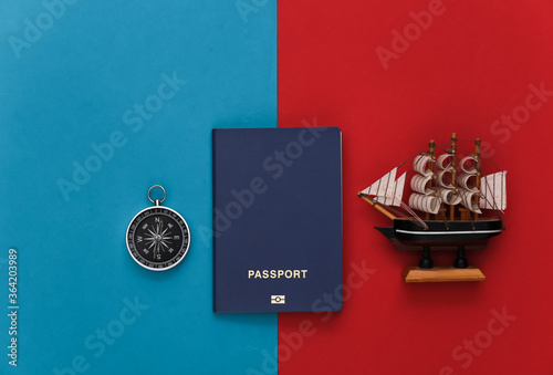 Compass, passport and ship on a red-blue background. Travel, adventure flat lay. Top view