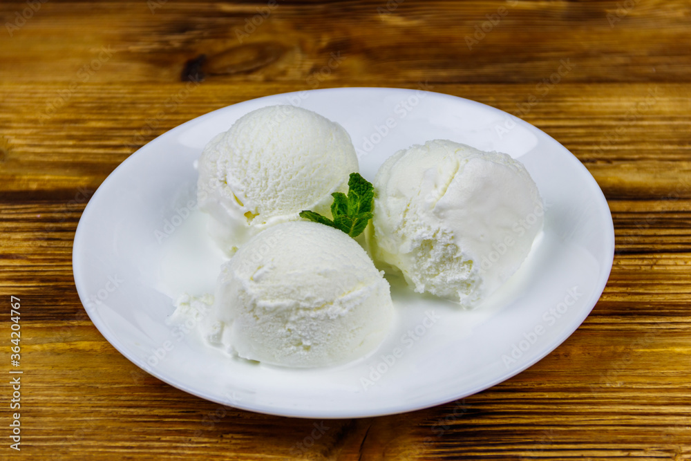 Vanilla ice cream in white plate on a wooden table Vanilla ice cream in white plate on a wooden table