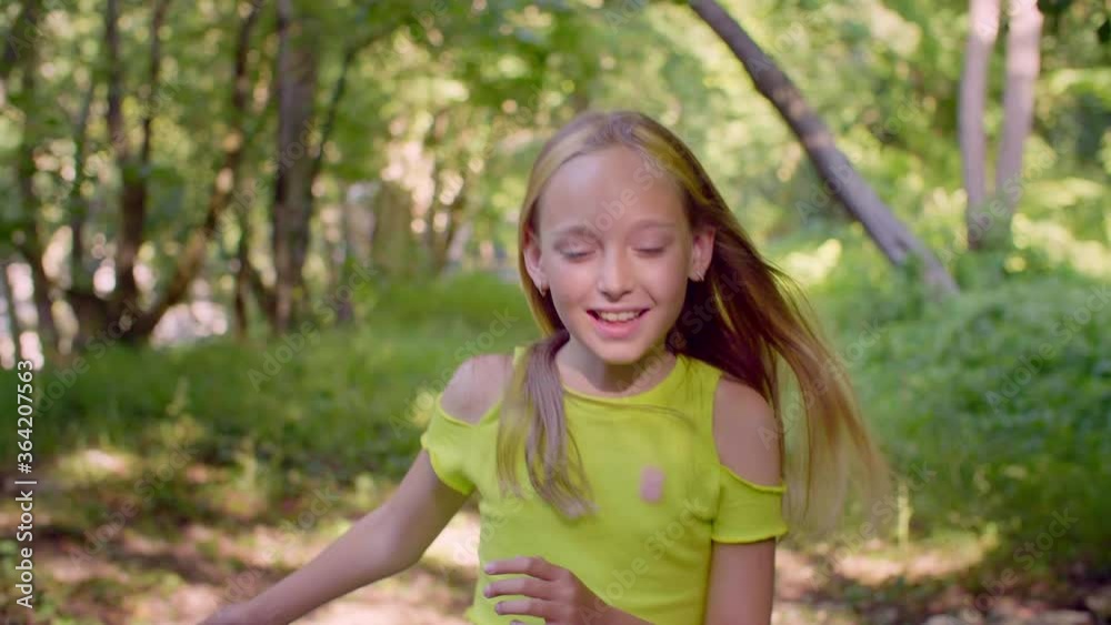 Smiling teen girl enjoying forest walk at sunny day on summer holiday in countryside. Portrait cheerful girl teenager walking in sunny forest at summer vacation. Smiling teen girl enjoying forest walk at sunny day on summer holiday in countryside. Portrait cheerful girl teenager walking in sunny forest at summer vacation.