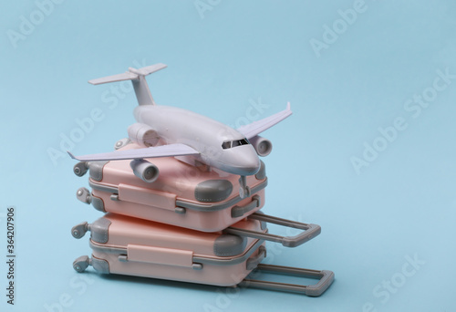 Travel, vacation or tourism concept. Two mini travel luggage suitcase and air plane on a blue background