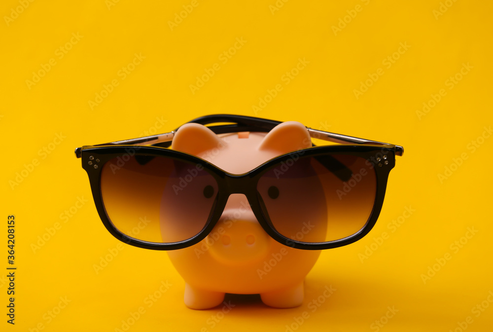 Piggy bank in sunglasses on a yellow background Piggy bank in sunglasses on a yellow background