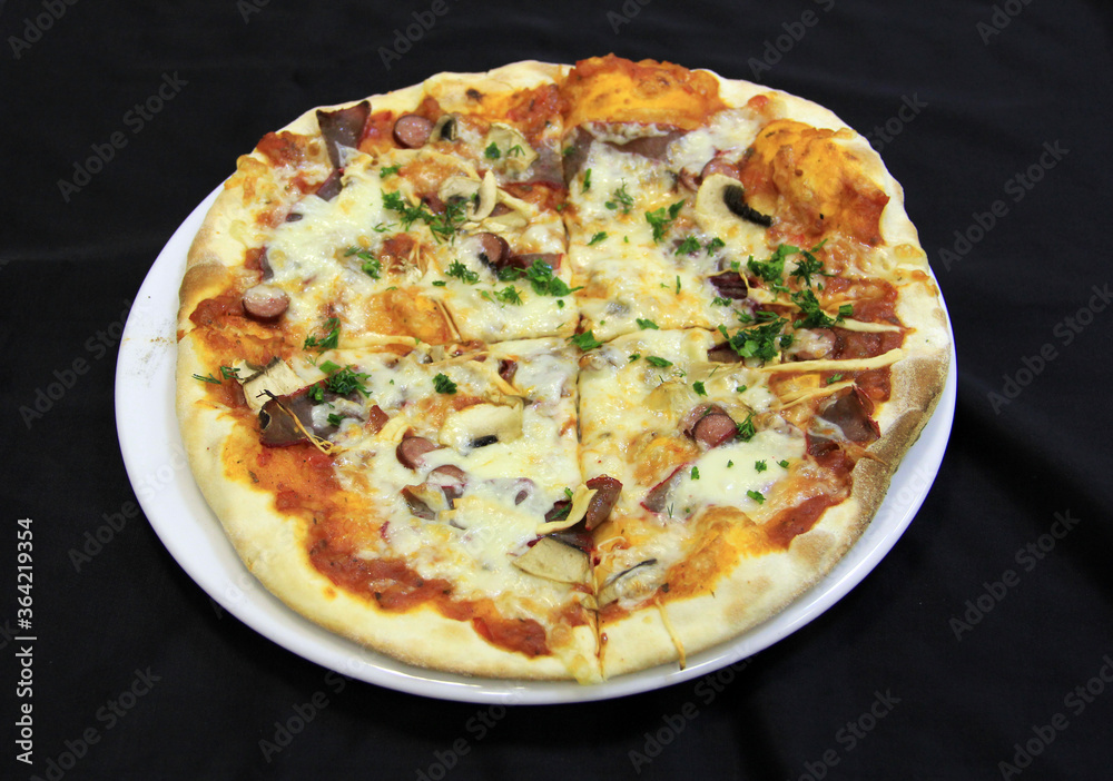 Meat pizza with cheese, mushrooms and dill on a white plate