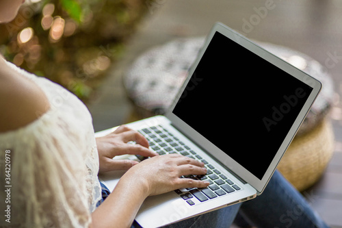 Young woman working on laptop in garden, selective focus.
