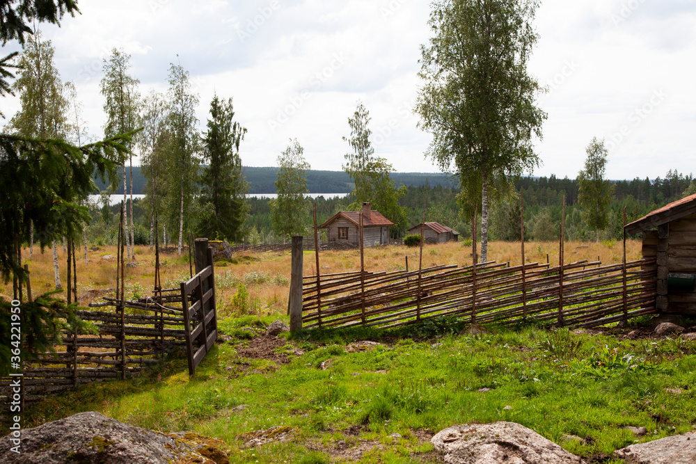 An old farm with an old wooden fence and some houses 