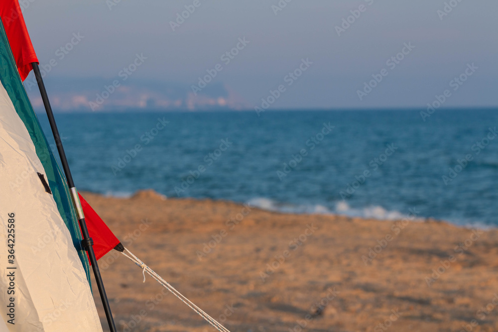Tent on the sandy shore against the background of the sea.