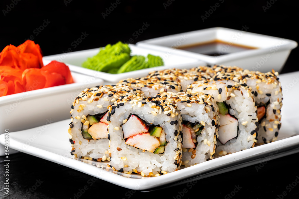 Rolls with crab meat, cucumber and sesame seeds on a white plate on a dark background. Sushi menu. Japanese food. Rolls with crab meat, cucumber and sesame seeds on a white plate on a dark background. Sushi menu. Japanese food.