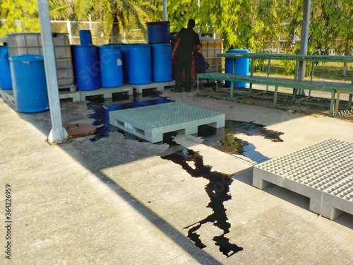 Black liquid chemicals leaking from the tank into the floor.