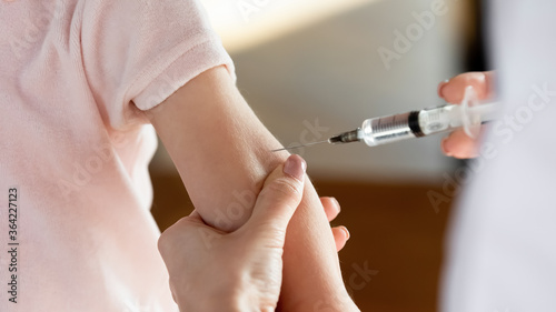 Close up female hands holding syringe  doctor vaccinating little patient at meeting in clinic  therapist pediatrician gp making prick  injection to preschool girl  children healthcare concept