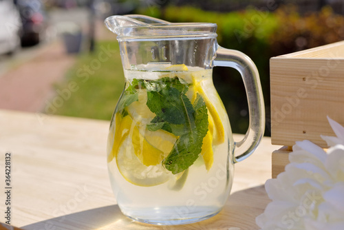 Glass jug with fresh cool homemade lemonade standing on wooden market stall