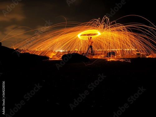 Abstract,Long exposure of swirling flame sparks arcing in circle at the night is black background.