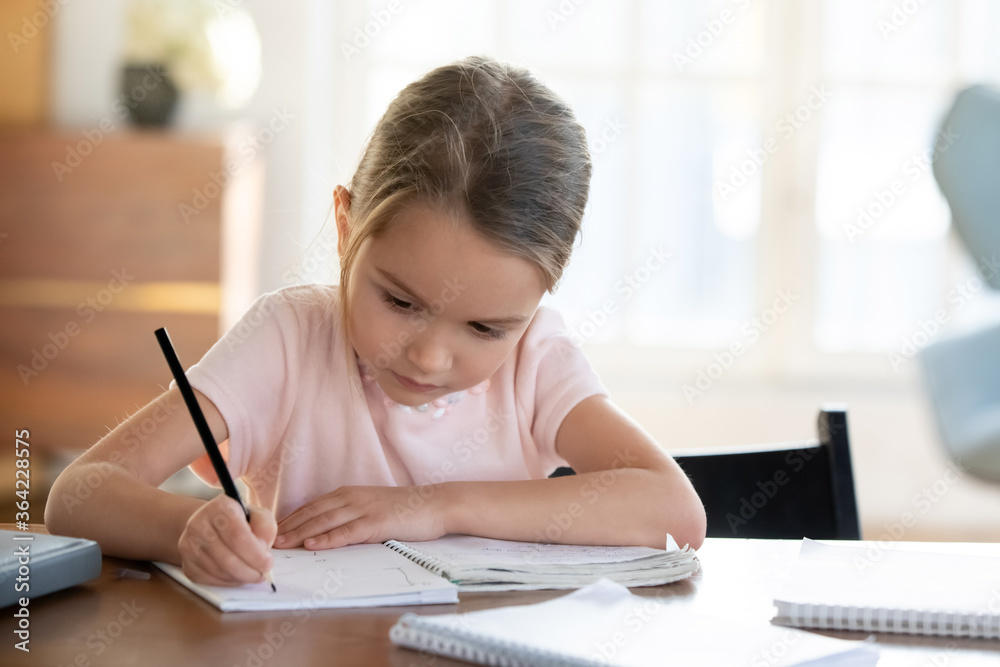 Busy little girl writing or drawing with pen in notebook close up, pretty focused child schoolgirl preparing school homework, assignments, sitting at work desk at home, homeschooling concept Busy little girl writing or drawing with pen in notebook close up, pretty focused child schoolgirl preparing school homework, assignments, sitting at work desk at home, homeschooling concept