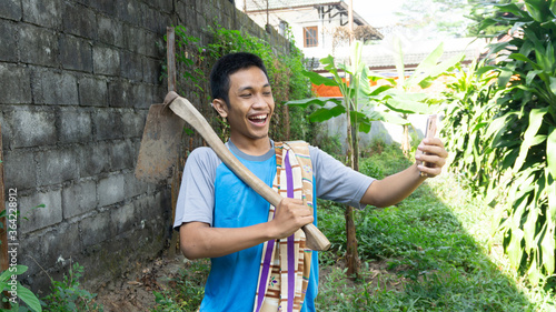 Asian man is gardening and looking at a cellphone with a WOW expression or shocked photo