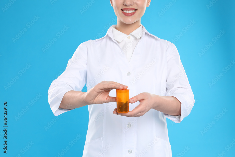 Professional pharmacist with pills on light blue background, closeup Professional pharmacist with pills on light blue background, closeup