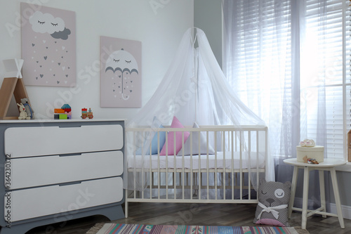 Baby room interior with cute posters, chest of drawers and comfortable crib © New Africa