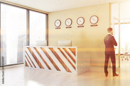 Man in beige office hall with reception and clocks