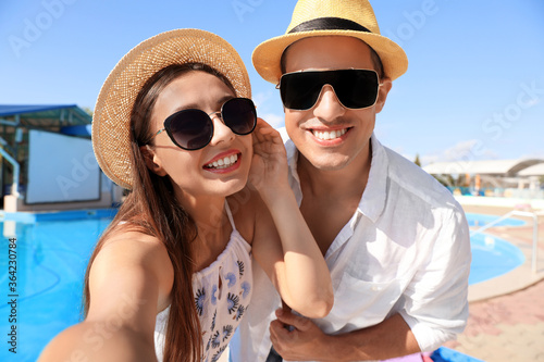 Happy couple taking selfie near swimming pool. Summer vacation © New Africa
