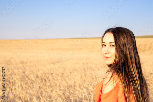 young brunnete women looking at camera on wheat field. 