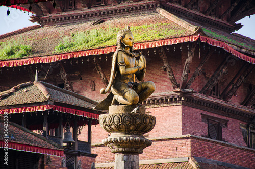 Statue of Malla King on top af o column, amongst Patan Durbar square temples in Kathmandu, Nepal photo