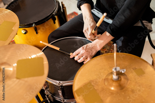 Murais de parede Hands of young casual drummer taking drumsticks from top of black drum