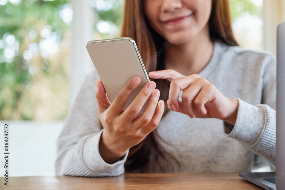 Fototapeta premium Closeup image of a beautiful asian woman holding and using mobile phone