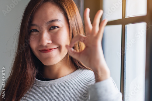 Closeup image of a beautiful young asian woman making and showing ok hand sign