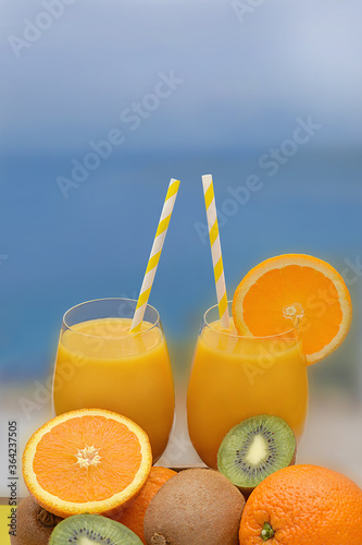 Orange juice with fresh fruit on a beach