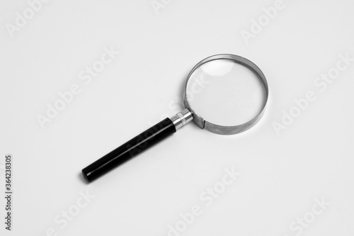 Black handle and metal rim Magnifying glass isolated on a white background. High-resolution photo.