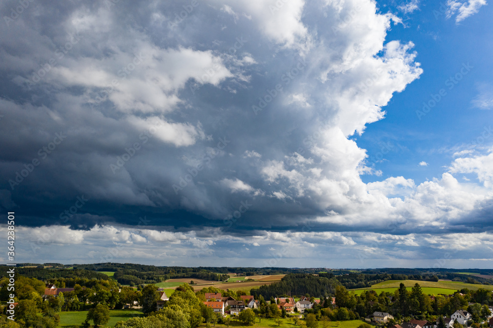 Gewitterwolken über einer sonnigen Dorflandschaft Gewitterwolken über einer sonnigen Dorflandschaft