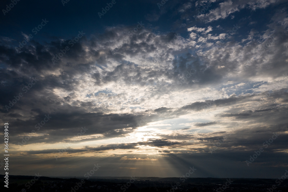 Sonnenstrahlen durchbrechen Wolken an einem bewölkten Abendhimmel