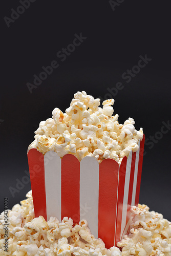 Popcorn in paper box on black background, top view. Space for text.