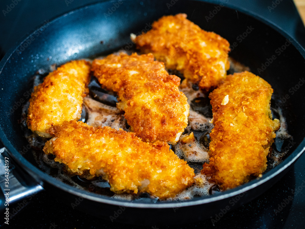 Breaded chicken breast nuggets frying in pan Breaded chicken breast nuggets frying in pan