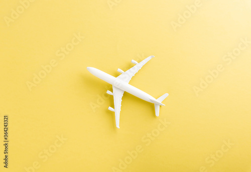 World Tourism Day, Top view flat lay of minimal toy model plane, airplane with copy space, studio shot isolated on a yellow background, accessory flight holiday concept