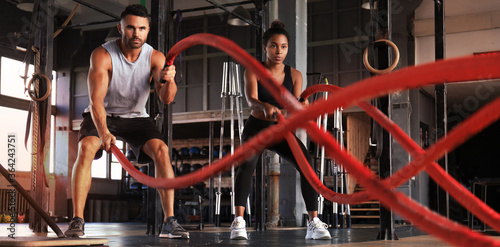 Bilde på lerret Athletic young couple with battle rope doing exercise in functional training fitness gym