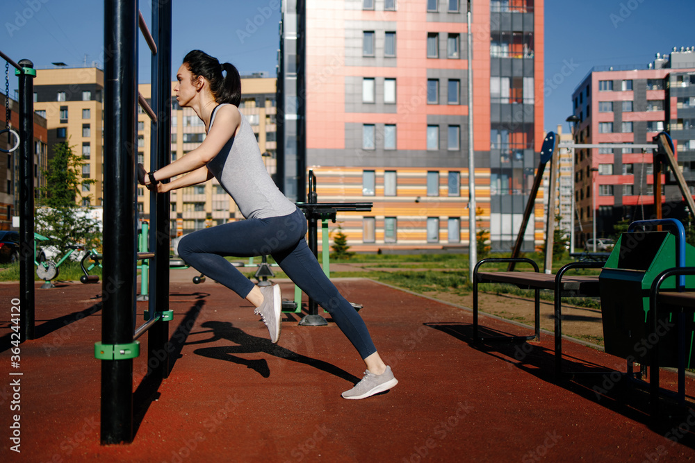 A woman is doing exercises on the street at the Playground. Concept of good physical shape and healthy lifestyle