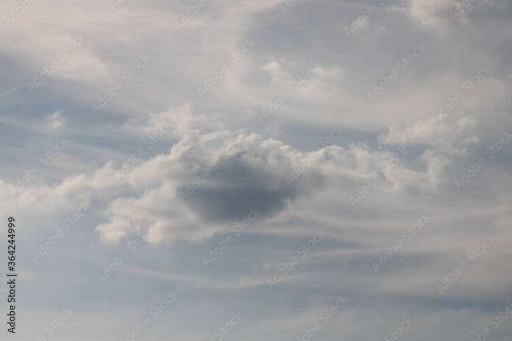 Single dark cloud on a light cloudy blue sky