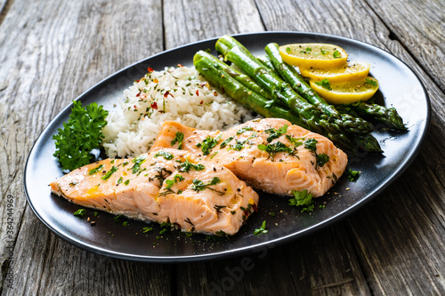 Steamed salmon fillet with basmati rice, asparagus and vegetables on wooden table