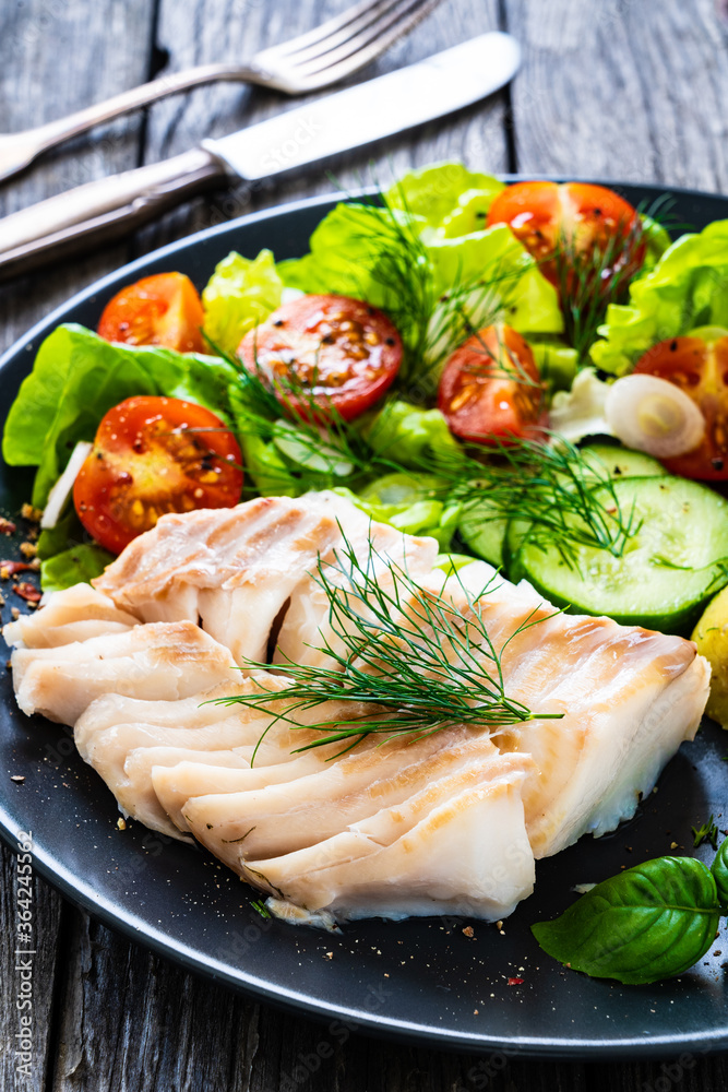 Fish dish - fried cod fillet with vegetables on wooden table
Fish dish - fried cod fillet with vegetables on wooden table