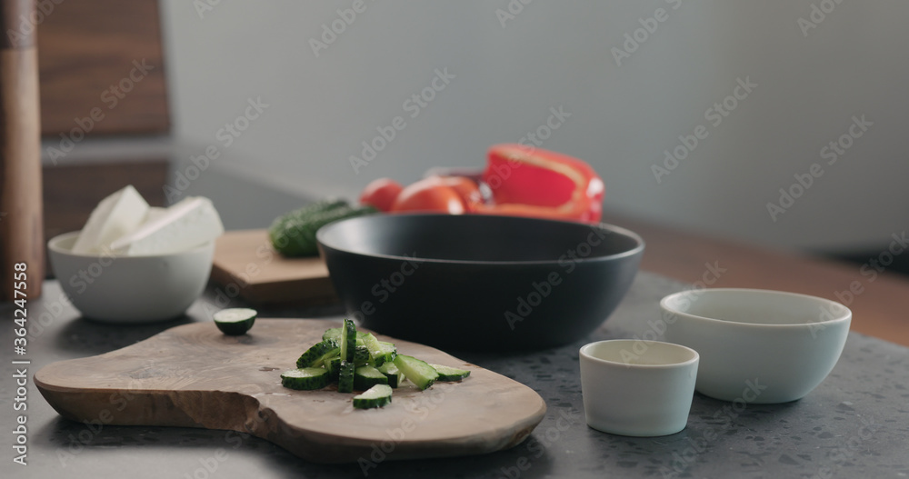 Man chopping cucumber on olive wood board for greek salad Man chopping cucumber on olive wood board for greek salad