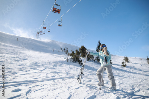 A woman posing with ski in mountain ski resort in winter season,sunny day