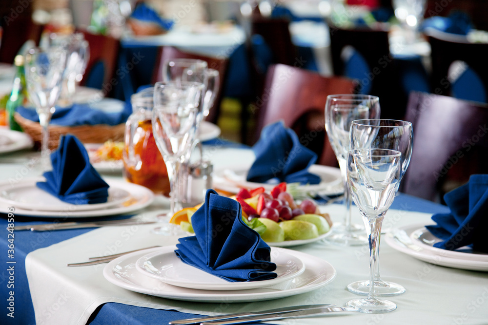 Restaurant table with empty wineglasses and plates for banquet or wedding dinner