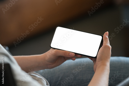 Fototapeta Naklejka Na Ścianę i Meble -  Young woman hold smarphone with white screen while sitting in a chair