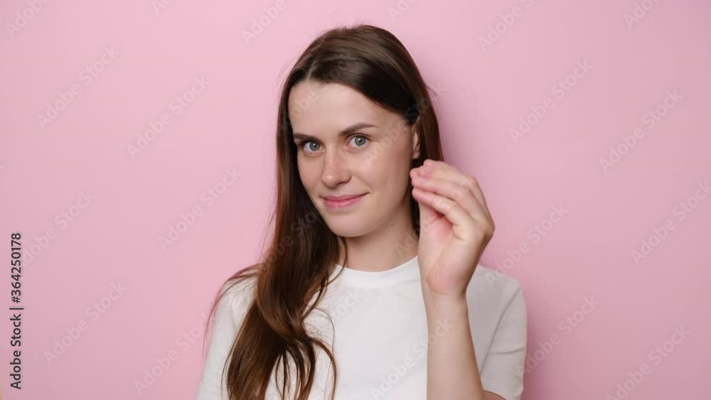 Young brunette woman isolated on pink studio background showing money gesture, having cunning plan for earnings big income, looking at camera smiling slyly, dressed in t-shirt, asking cash allowance Young brunette woman isolated on pink studio background showing money gesture, having cunning plan for earnings big income, looking at camera smiling slyly, dressed in t-shirt, asking cash allowance