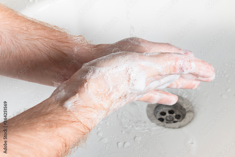 Man use soap and washing hands under the water tap. Hygiene concept hand detail.