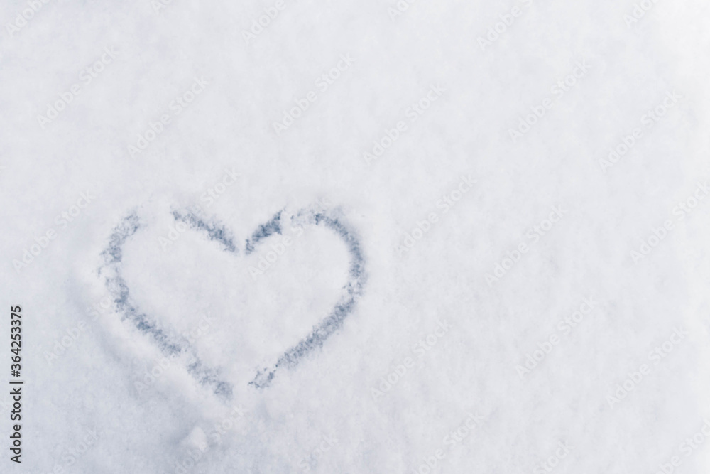 A symbol of love the heart painted on the white snow. Background. Copy space.