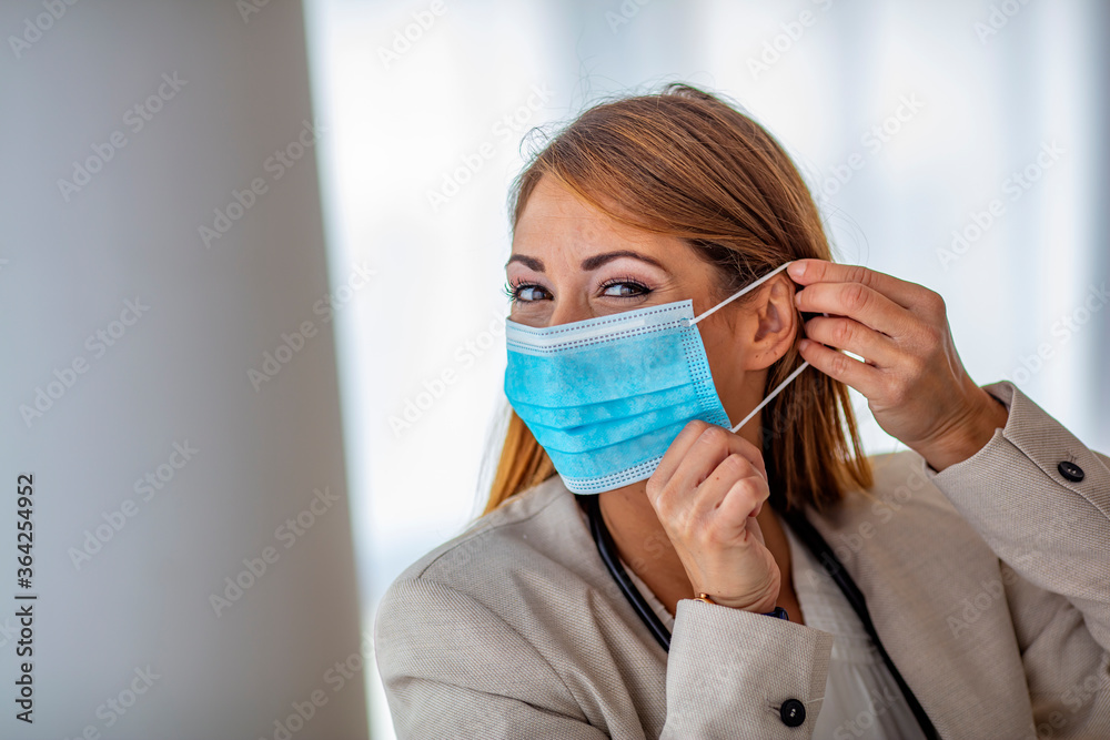 Young beautiful woman put on medical mask for protection against coronavirus contagious disease. on a light background. Medic holding face mask. Preventive measure against coronavirus COVID-19.