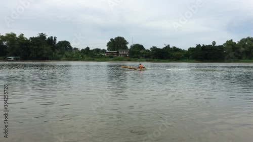 A man drives the traditional long tail boat on the surface of the river in urban area
