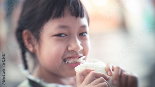 Asian child girl eating some bread with smile and happy
