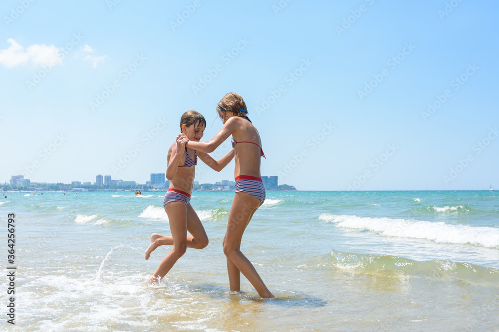 Two girls joyfully play and run along the seashore