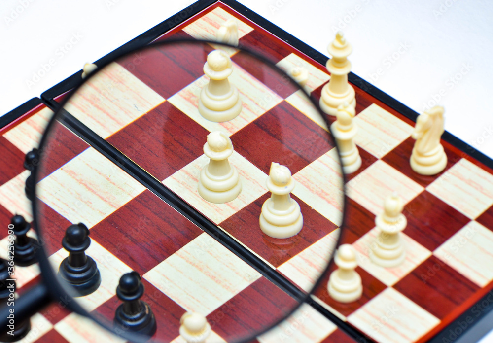 Magnifying glass and chess, chessboard on a white background. Chess view through a magnifying glass Magnifying glass and chess, chessboard on a white background. Chess view through a magnifying glass