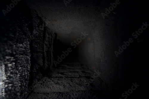 the background texture of a shaft well pipe furnace which is covered with a large layer of black soot that goes into the darknes
